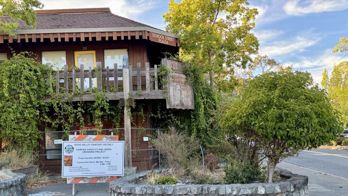 The School Street Plaza site as it stands, a low timber office building with a construction notice at the curb.