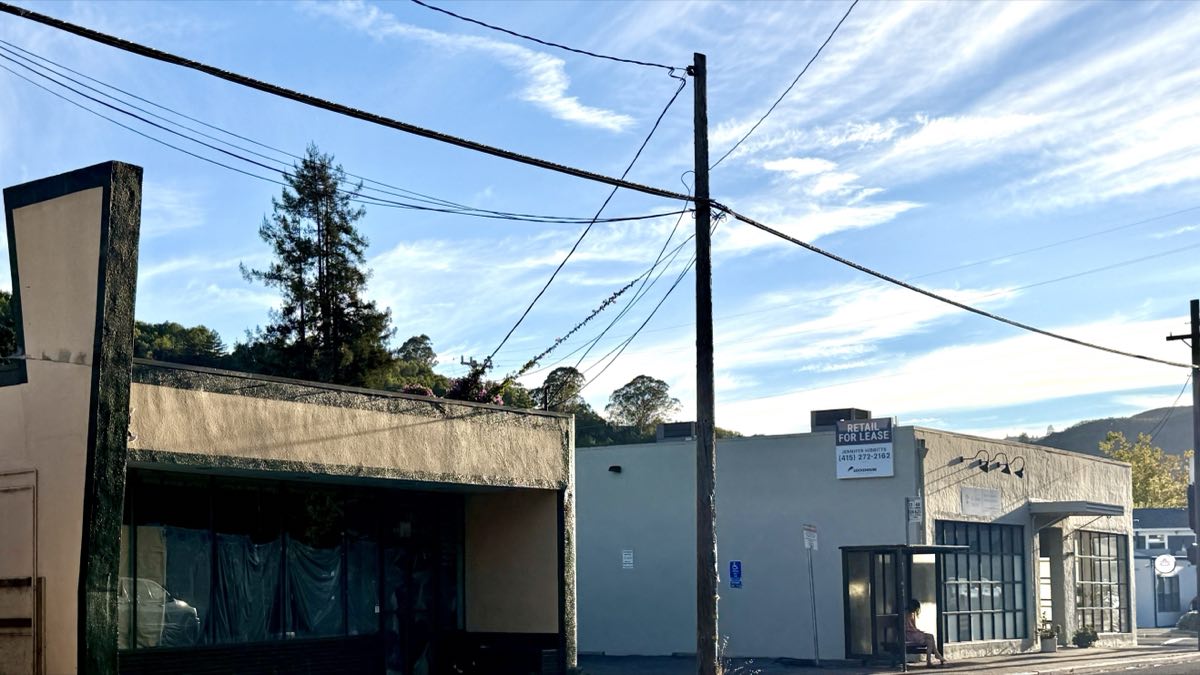 Two adjoining empty units on Sir Francis Drake Boulevard, one with plastic sheeting in the windows and one with a RETAIL FOR LEASE sign.