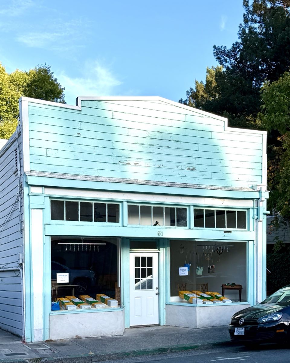 A mint green wooden shopfront at number 61, empty but for a few boxes on the floor.