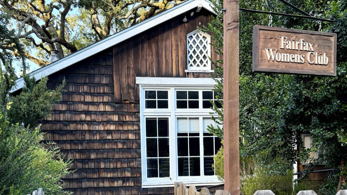 The Fairfax Women's Club, a brown shingled building under a spreading oak, its hanging sign at the gate on Park Road.